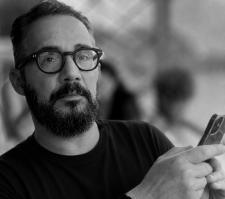 Portrait of Petros Isaakidis, wearing glasses, holding a phone.